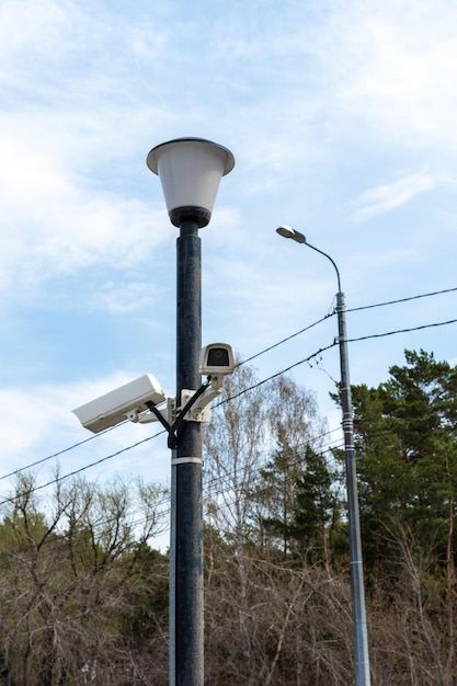 林道の防犯の横にある街灯柱に取り付けられた監視カメラcctvカメラ都市の防犯何が起こっているのかを隠した撮影現代の技術と設備