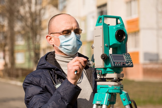 Surveyor in a mask works with a total station