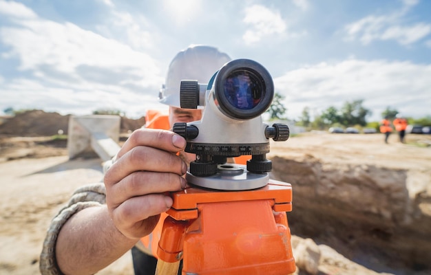 Photo surveyor worker with theodolite equipment at construction site