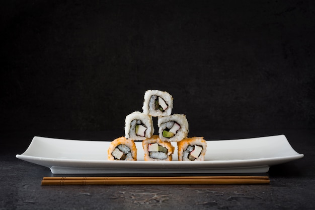 Ассортимент суши на белой тарелке на черном