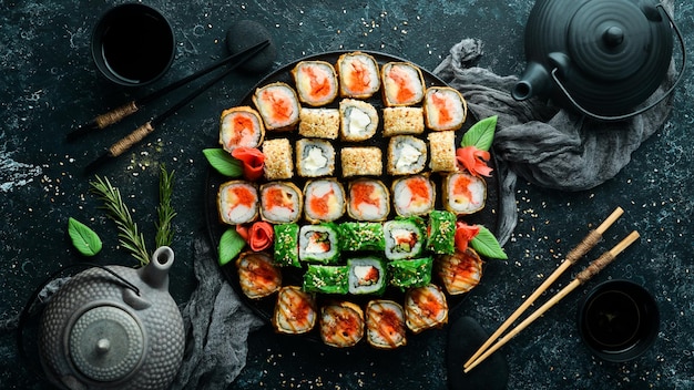 Меню суши-бара Набор цветных вкусных суши-роллов на черных тарелках Вид сверху