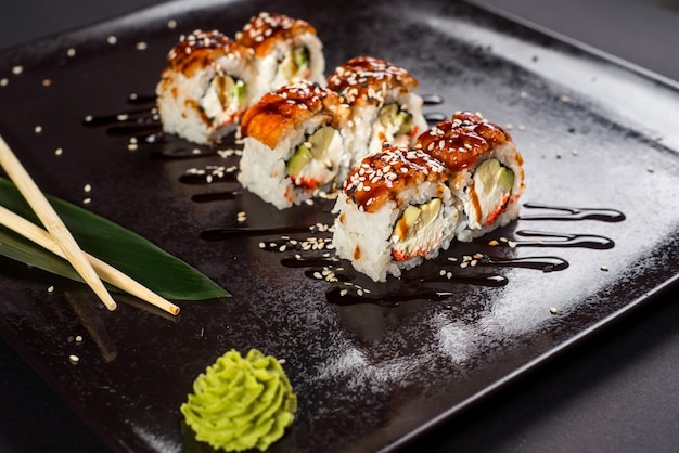 Sushi california roll met saus en sesam op zwarte plaat