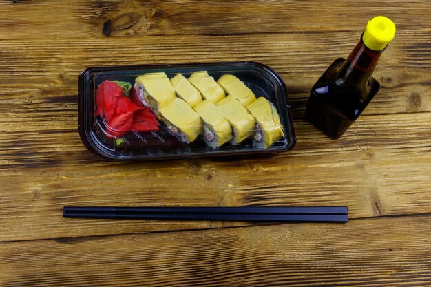 Sushi cheese rolls in plastic box on wooden table