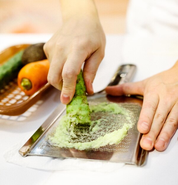 Foto chef di sushi grattugiando wasabi fresco radice di wasabi fresca preparata per il sushi nigiri