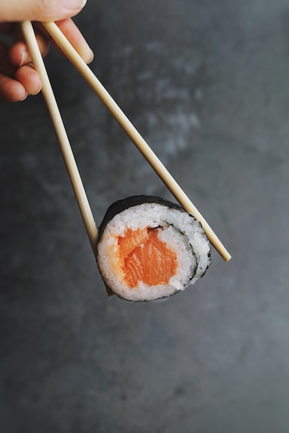 Sushi and chopsticks over dark background