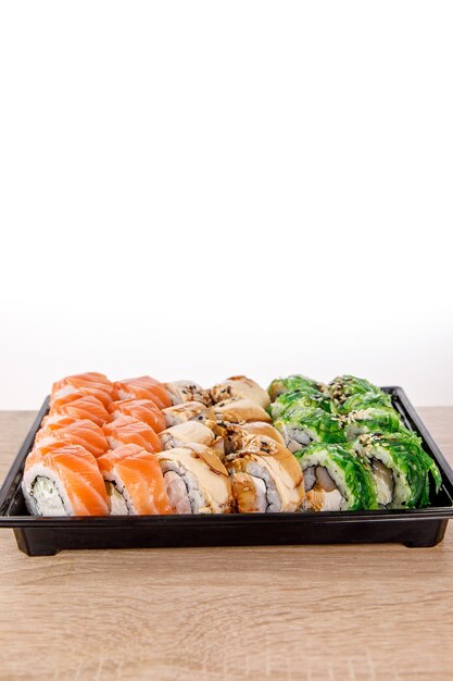 Consegna del sushi. diversi rotoli in confezione di plastica nera composizione vista dall'alto. cibo giapponese e asiatico. menu o concetto di consegna con spazio per il testo.