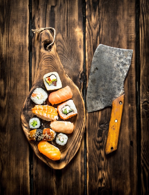 Sushi en broodjes met zalm en oude bijl. Op houten achtergrond.