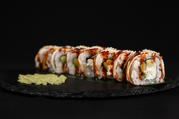 Sushi en gebakken knoflookgarnalengarnalen op een stenen bord met zwarte achtergrond