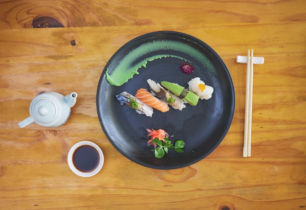 Sushi eten en eetstokjes in een Aziatisch restaurant van bovenaf voor lekker eten of traditionele keuken Zalmmenu en zeevruchten met een Chinees gerecht op een tafel in een lokaal eetcafe voor honger of voeding