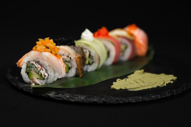 Sushi and fried garlic shrimps prawn on a stone plate with black background