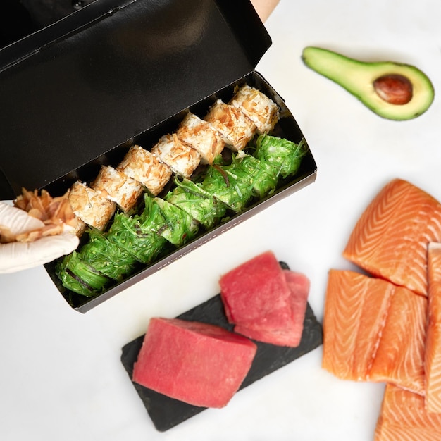 Sushi to go 개념 검정 종이 봉지에 스시 롤과 젓가락이 있는 테이크아웃 상자의 상위 뷰 Maki Sashimi Salmon Tuna Wakame AsianJapaneseTakeaway 일본 음식