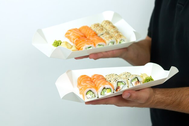 Sushi levering concept, koerier man met sets van sushi in eco-containers van papier