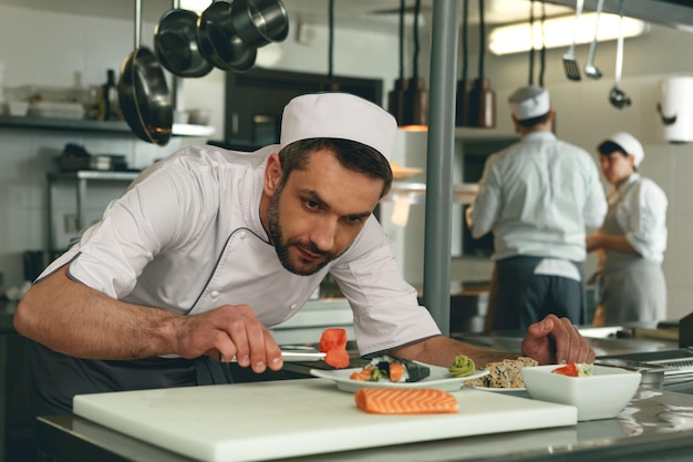 Sushi master prepares sushi for serving in modern commercial kitchen