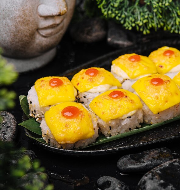 Sushi met cheddar kaas op zwart bord met gele curry