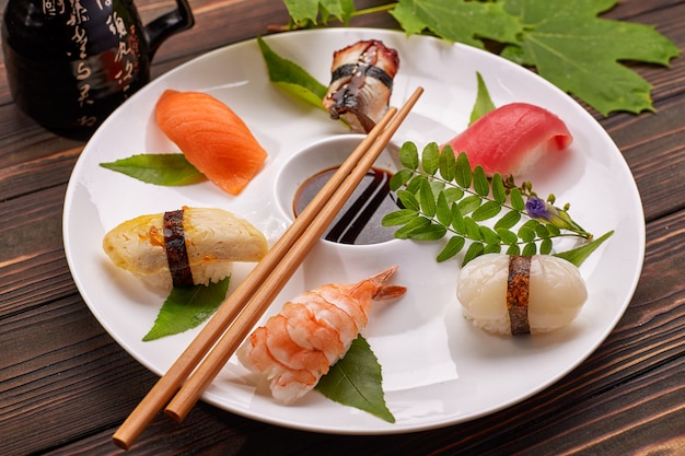 Sushi nigiri met tonijn, zalm, garnalen, coquille, paling, omelet, op een wit bord met sojasaus