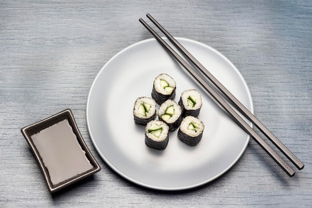Sushi nori rolls and chopsticks on blue plate