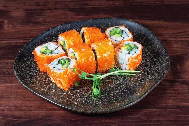 Sushi of rijstrolletjes met rode kaviaar en komkommer op een houten tafel. Selectieve aandacht. Traditioneel oosters eten