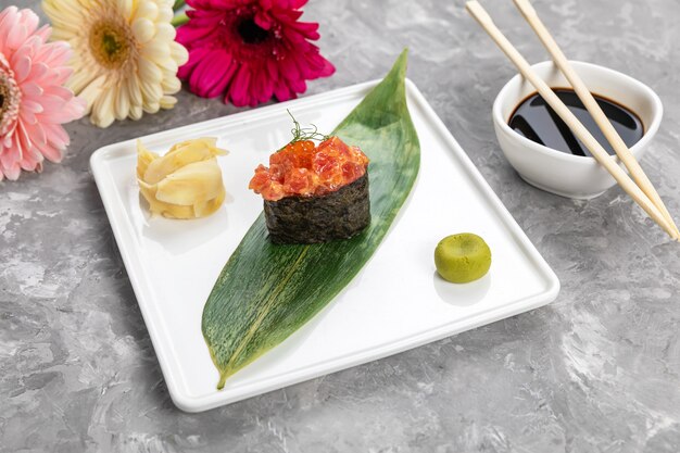 Sushi op een bananenblad met saus op een witte plaat