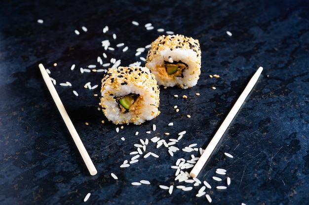 Sushi op een zwarte tafelplaat met houten eetstokjes. Japans eten in restaurant.