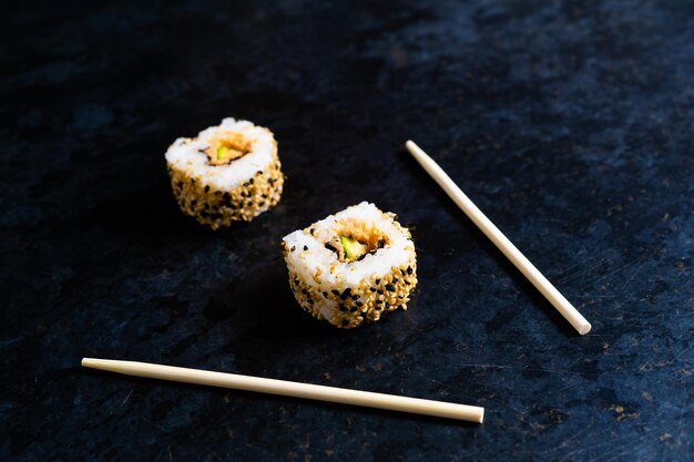 Sushi op een zwarte tafelplaat met houten eetstokjes. Japans eten in restaurant.