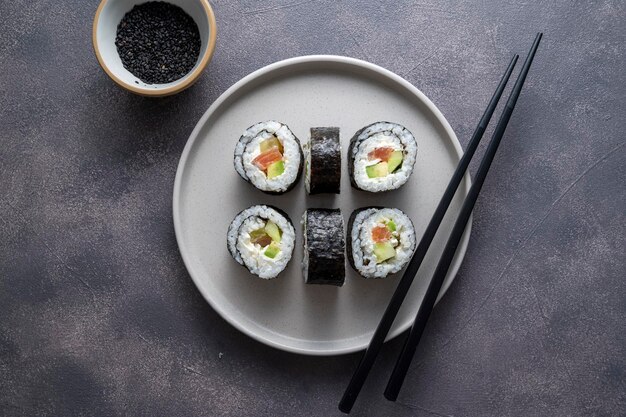 Sushi op rond bord met stokjes sojasaus gember Huisgemaakte rolletjes met zalm, avocado en komkommer