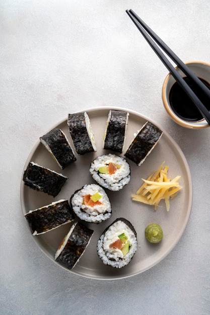 Sushi op rond bord met stokjes sojasaus gember Huisgemaakte rolletjes met zalm, avocado en komkommer