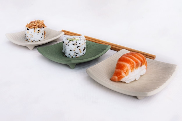 sushi pieces in neutral colored square plates with chopsticks.