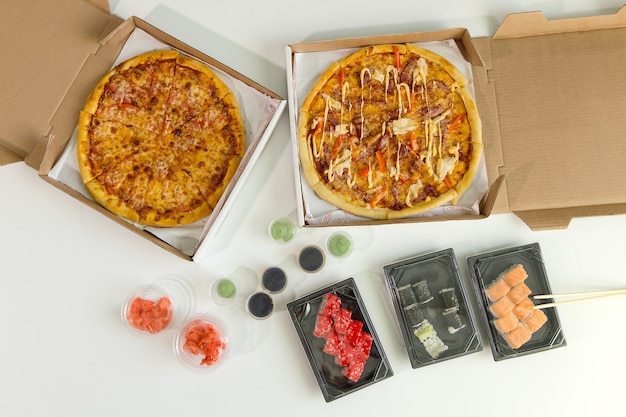 Sushi and pizza. Concept of business lunch, white background. Calorie food.