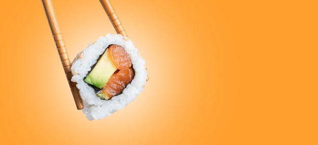 Photo sushi roll in chopsticks with copy space