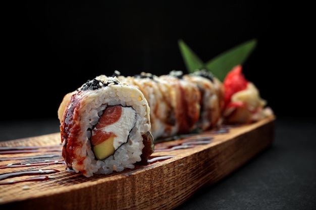 Sushi roll Golden dragon with eel salmon tobiko and cream cheese on a wooden board