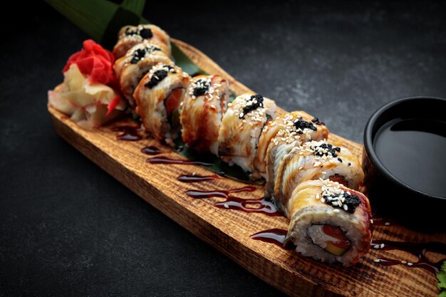 Photo sushi roll golden dragon with eel salmon tobiko and cream cheese on a wooden board