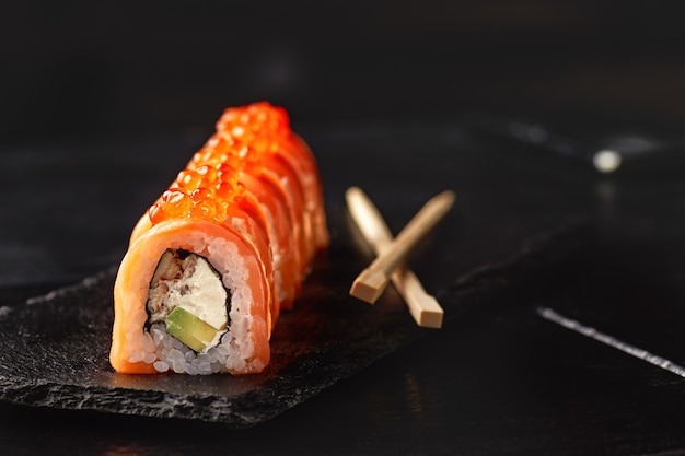 Sushi roll maki futo japans eten op een zwarte stenen plaat in de handen van een ober.