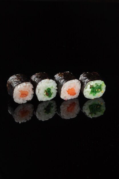 Sushi roll met reflectie op een zwarte achtergrond. Een restaurant met Japanse keuken. Vrouwenhanden met sushibroodjes