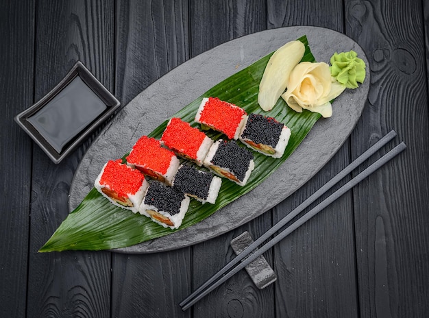 Sushi roll met zalm roerei tobiko kaviaar Traditionele heerlijke verse sushi roll ingesteld op een zwarte achtergrond Sushi menu Japanse keuken restaurant Aziatisch eten