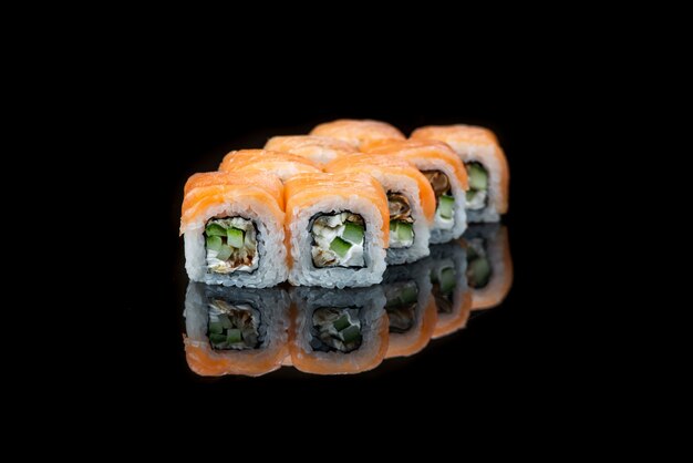 黒の背景に巻き寿司反射日本食をクローズアップ