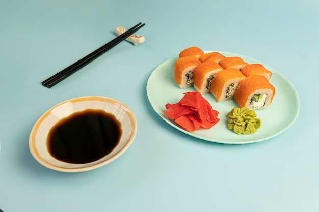 Sushi roll op een plaat sojasaus wasabi en gember op blauwe achtergrond