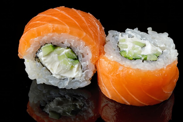 Sushi roll Philadelphia klassiek met zalm crème kaas en komkommer op een zwarte spiegel