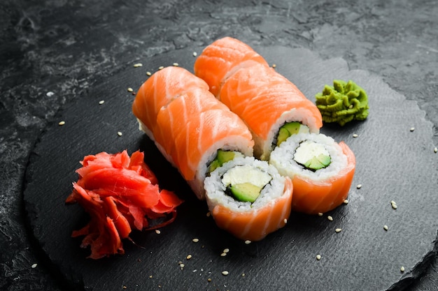 Sushi roll (Philadelphia) with salmon, avocado, cream cheese on a black background. Sushi menu. Japanese food.