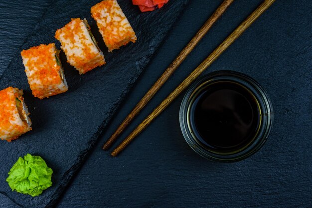 Sushi roll philadelphia with salmon rice cheese cucumber avocado and caviar on a slate board Japanese food Top view