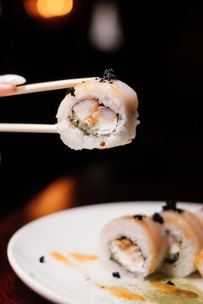Суши-ролл на белой тарелке с палочками для еды и икрой японской кухни