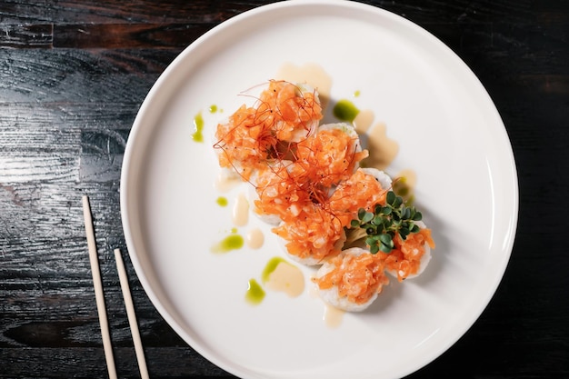 Foto rotolo di sushi impostato su piatto bianco con le bacchette