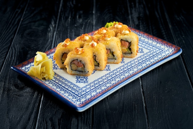 Foto rotolo di sushi in tempura con salmone, avocado e caviale.