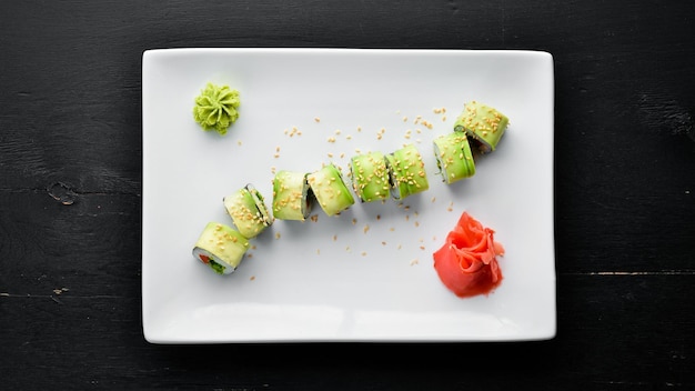 Sushi roll with avocado cucumber and tomato Japanese cuisine Top view On a black background