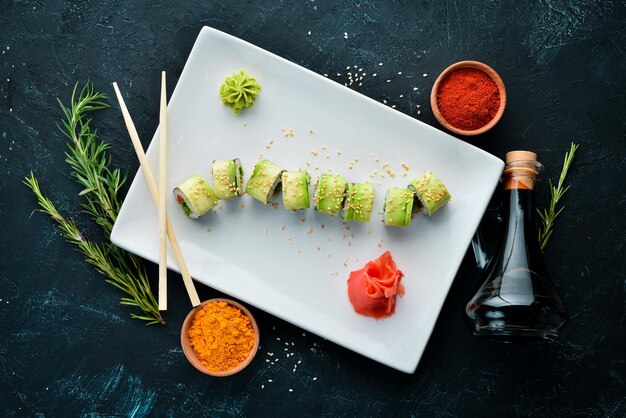 Sushi roll with avocado cucumber and tomato Japanese cuisine Top view On a black background