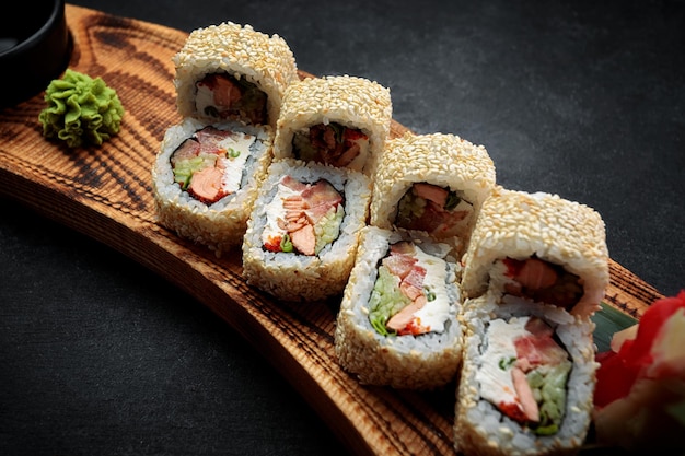 Sushi roll with fried salmon tomato cheese green onion on a wooden board