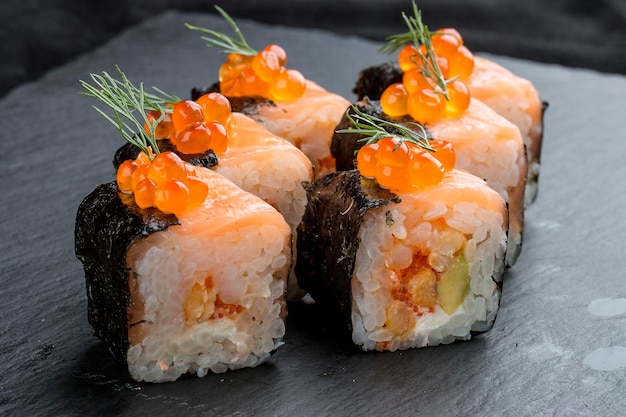 Sushi roll with salmon and caviar on black background
