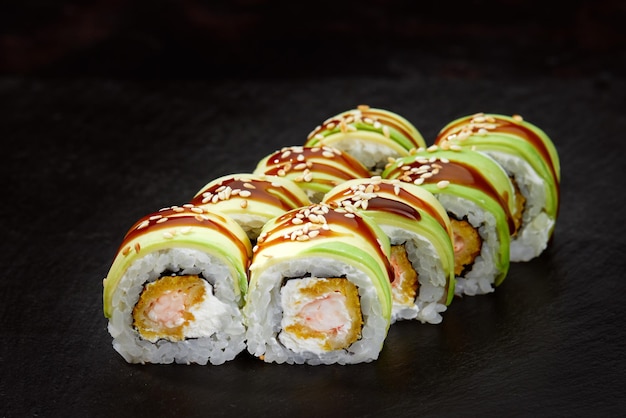 Photo sushi roll with tuna avocado and cream cheese on a black background