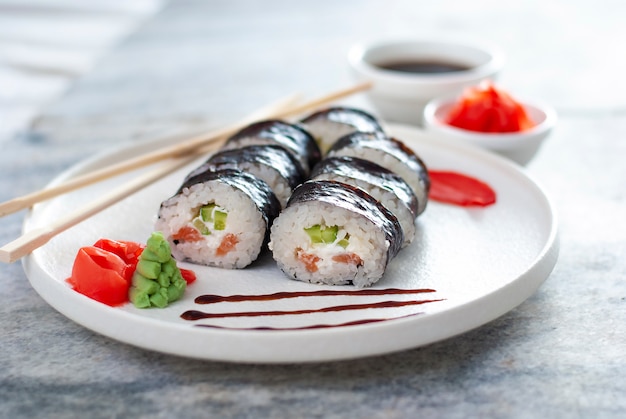 Sushi rolls cibo asiatico con riso e frutti di mare sul piatto bianco con zenzero e wasabi piccante