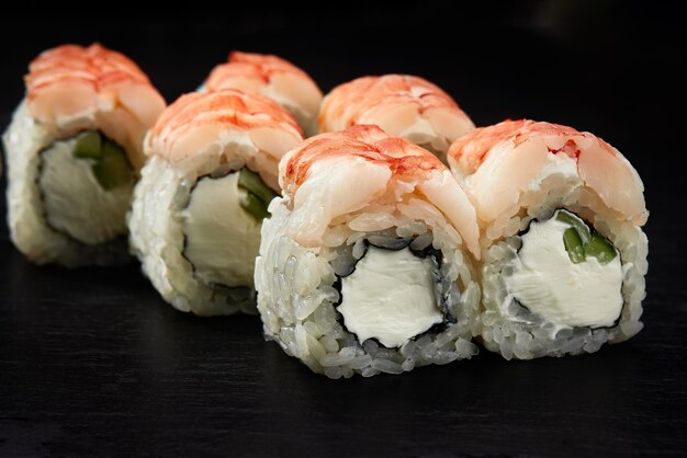 Sushi rolls california with snow crab cream cheese cucumber sesame seeds and masago caviar isolateed on black background with reflection Japanese oriental cuisine