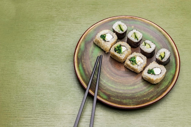 Sushi rolls and chopsticks on green plate